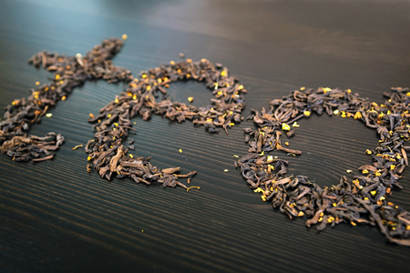 Tea word, made from tea and mixed forest fruits on a dark brown wooden Board.Top view.の写真素材