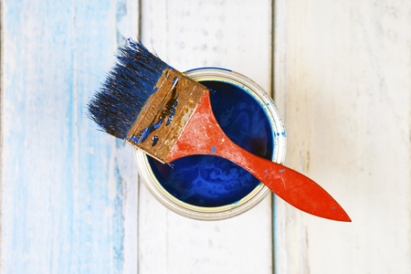 Full of blue paint tin and paint brush on it, isolated on wooden  backgroundの写真素材
