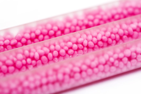 Drinking straws on white background with copy space. Top view of pink eco-friendly straws with strawberry balls for summer cocktails.の写真素材