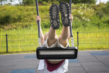 Boy swinging on the playground at the day timeの写真素材