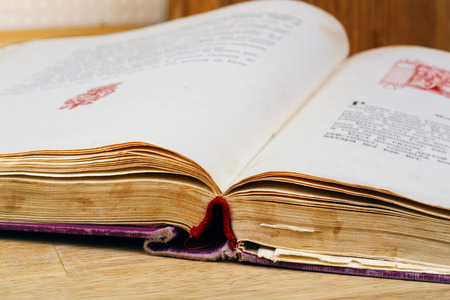 Close-up of opened old book against wooden background.の写真素材