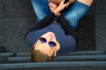 Guy sitting with sun glasses and phone. Top view