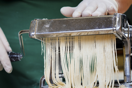 Process of production of  pasta. Fresh pasta and pasta machine on kitchen tableの写真素材