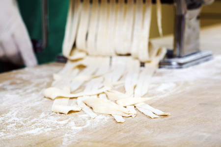 Process of production of  pasta. Fresh pasta and pasta machine on kitchen tableの写真素材