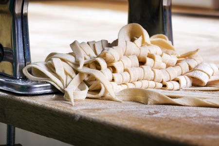 Process of production of  pasta. Fresh pasta and pasta machine on kitchen tableの写真素材