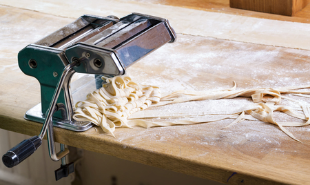 Process of production of  pasta. Fresh pasta and pasta machine on kitchen tableの写真素材