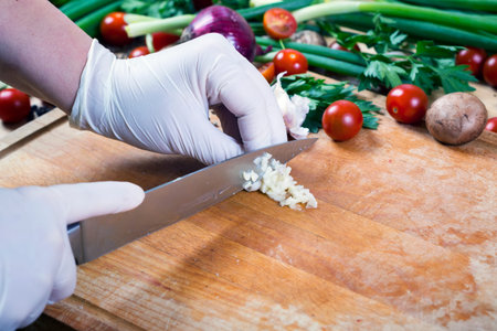 Woman chopping garlic on wooden board for cooking