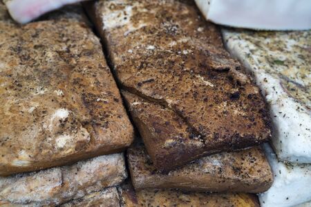 Pieces of Smoked Fat and Meat stacked smoked on traditional and natural wayr of a street market on a fair of traditional products, in Klaipeda, Lithuaniaの写真素材