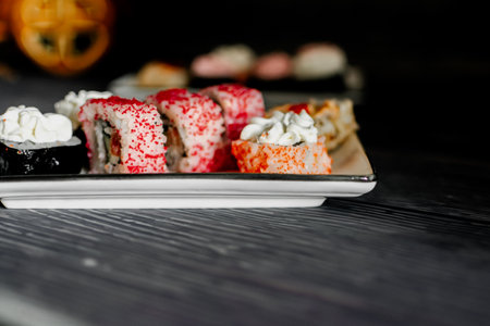 Sushi rolls on a white plate on a black wooden table.の写真素材