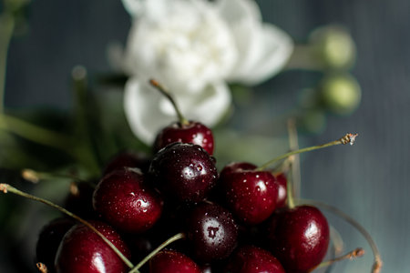 Fresh cherries in a glass vase on a dark wooden backgroundの写真素材