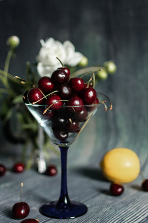 cherries in a glass vase on a wooden background. tinting. selective focusの写真素材