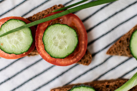 Cucumber and Tomato Slices on Rye Bread with Chivesの写真素材