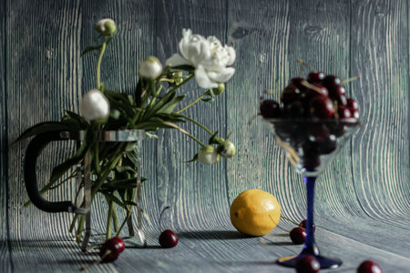 Still life with cherry, lemon and peony on a wooden backgroundの写真素材