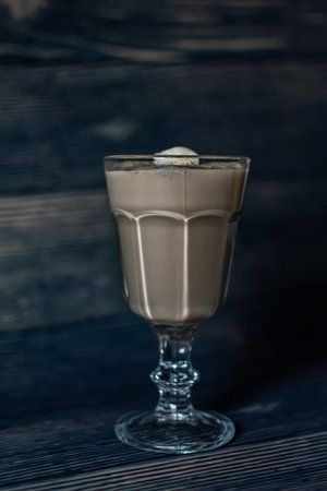 Coffee with milk in a glass on a dark wooden background