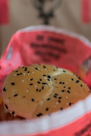 Bun with sesame seeds in a red plastic basket, closeupの写真素材