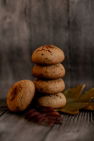 Stack of oatmeal cookies with autumn leaves on old wooden background.の写真素材