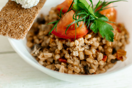 Buckwheat porridge with tomatoes and herbs on a white wooden backgroundの写真素材