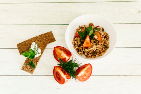 Porridge with tomatoes and herbs on a white wooden background.の写真素材