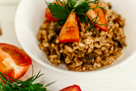 Risotto with tomatoes and herbs on a white wooden background. Selective focus.の写真素材