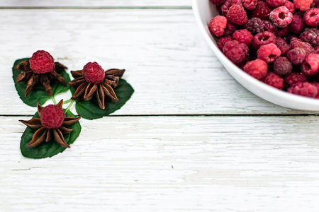Raspberries and star anise on a white wooden background.の写真素材