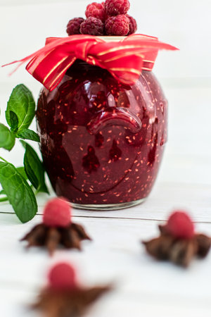 Raspberry jam in a glass jar with fresh raspberries and mint.の写真素材