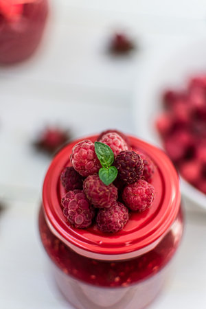 Raspberry jam in a jar with fresh berries on a white backgroundの写真素材