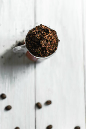 Coffee beans and ground coffee in a cup on white wooden backgroundの写真素材