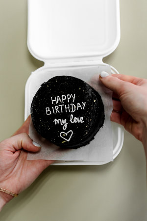 Happy birthday message on a black cake in a white box with a lidの写真素材