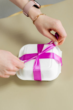 Woman's hands wrapping gift box with purple ribbon. Top view.の写真素材