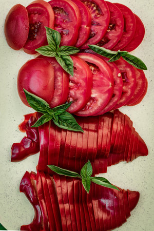 Sliced tomatoes with basil leaves on white background. Top view.の写真素材