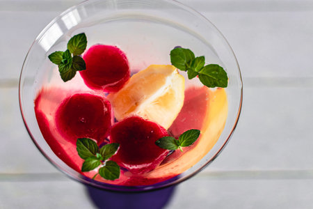 Refreshing summer drink with fruit and berries in martini glass