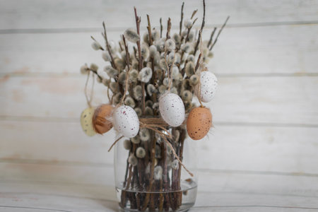 Easter eggs and willow branches in vase on wooden backgroundの写真素材