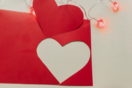 Valentine's day background. Red envelope with paper hearts and light garland