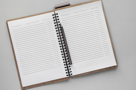 Open notebook with pen on grey background, top view, copy spaceの写真素材
