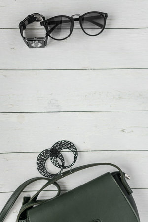 Women's accessories on a white wooden background. Glasses, handbag and belt.の写真素材