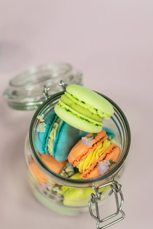 Colorful macaroons in glass jar on pastel background.の写真素材
