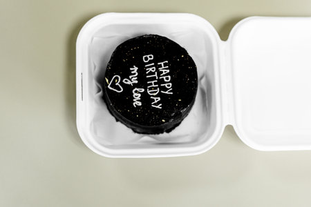 Black and white cake in a plastic container on a gray background.の写真素材