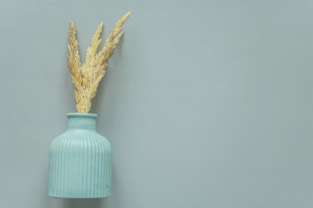 Ears of wheat in a blue vase on a gray backgroundの写真素材