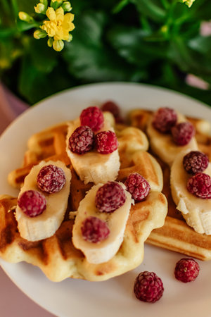 Belgian waffles with raspberries and banana on a plateの写真素材