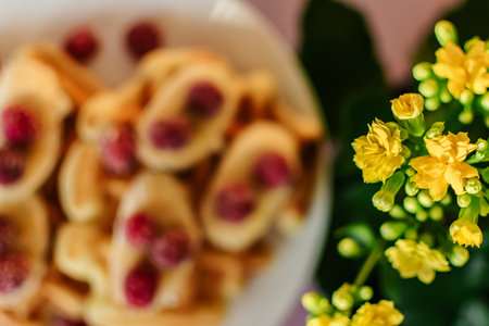 Pancakes with raspberries on a plate and yellow flowersの写真素材