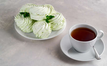 Handmade apple figured homemade marshmallow with mint on a white plate and tea in a white cup on a concrete table.の写真素材