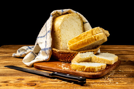 Fresh white wheat homemade bread on a wooden board on a wooden table, covered with a towel. Homemade...