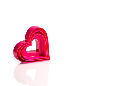 Plastic mold of pink color for cutting out heart cookies on a white background, different sizes....