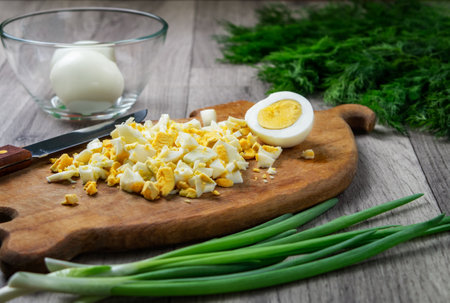 Boiled eggs, finely chopped on old wooden cutting board. Ingredient for salad. Home food concept. Natural food.の写真素材