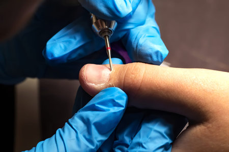 manicurist with gloves does a hardware manicure, mechanical processing of nails with a cutter,...