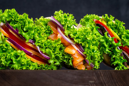 set of sandwiches with fresh salmon, ham, vegetables, salad. Home-made sandwiches. Healthy fast food. Dark background.の写真素材