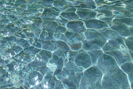 Clear water in the rays of the sun. Water background. Ripples on the surface of the water.