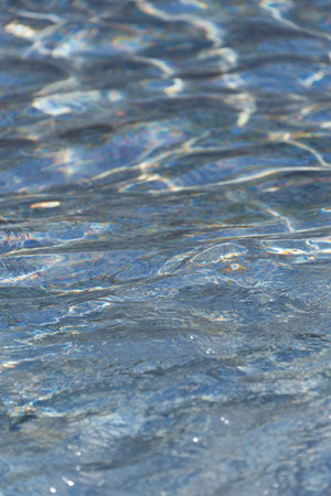 Clear water in the rays of the sun. Water background. Ripples on the surface of the water.