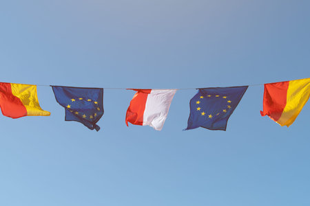 Flags of Warsaw, Poland and the European Union against a blue sky.