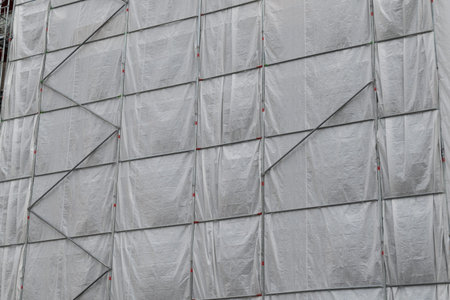 Gray tarpaulin and scaffolding. Building renovation and repair. Construction site.